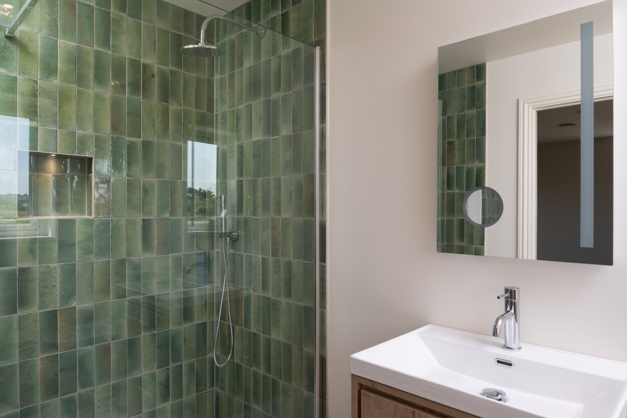 Green-tiled shower and timber vanity