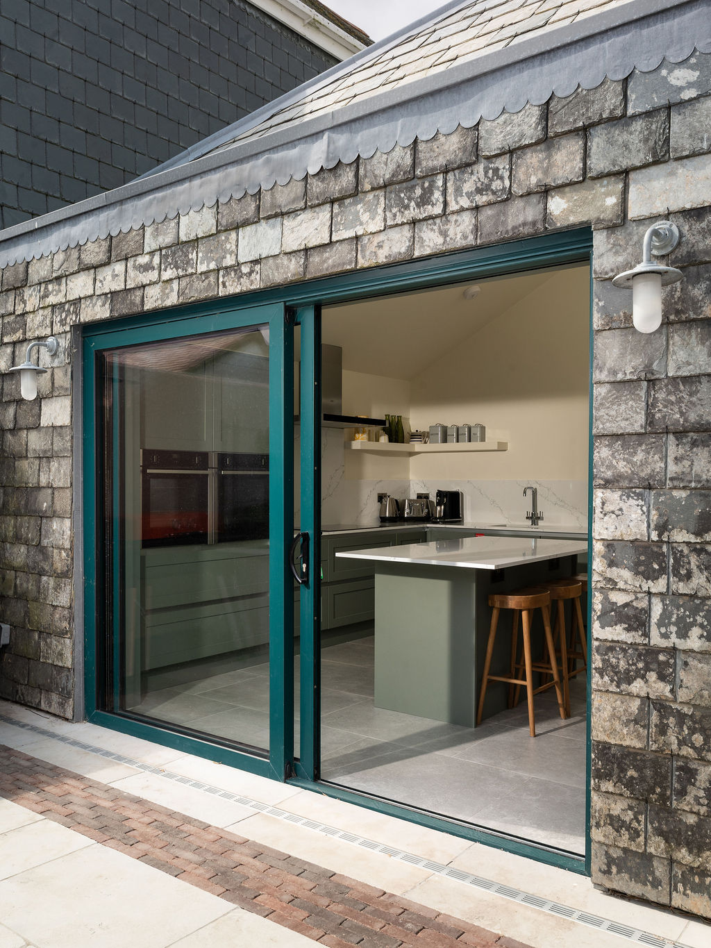 Sliding doors connecting the green kitchen to the courtyard