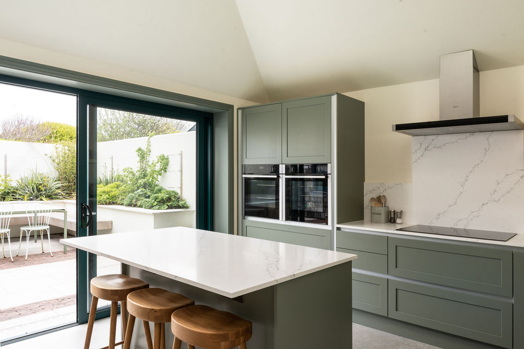 Green kitchen island opening onto the courtyard