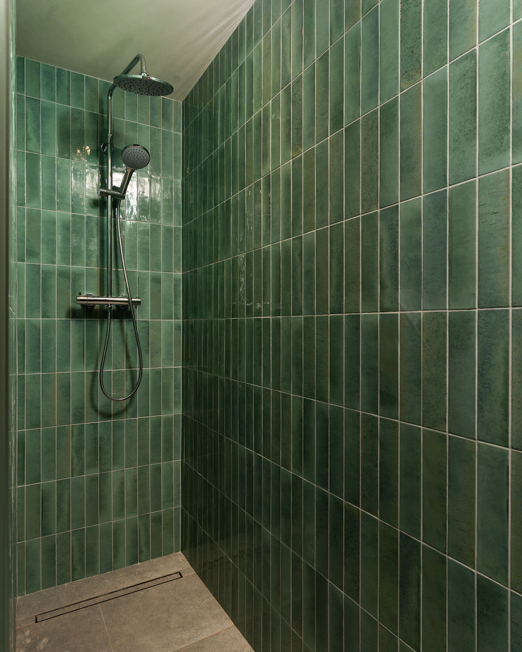 Walk-in shower lined with handmade green tiles