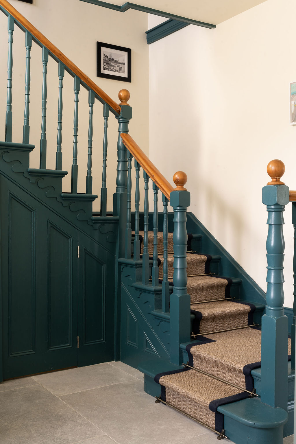 Restored staircase painted deep blue-green with timber handrail